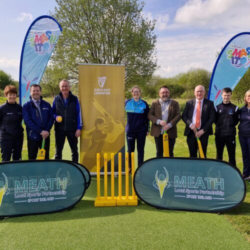 Group standing with cricket bats on a new wicket strip