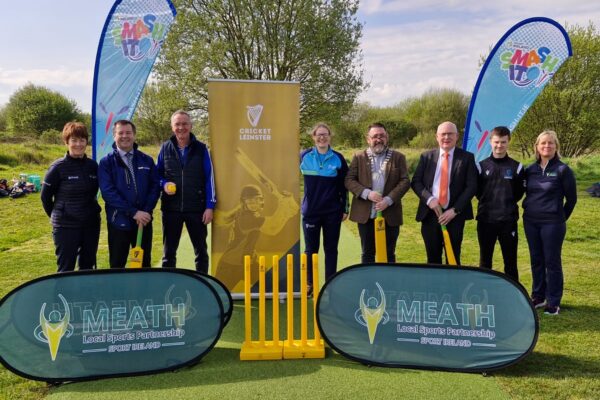 Group standing with cricket bats on a new wicket strip